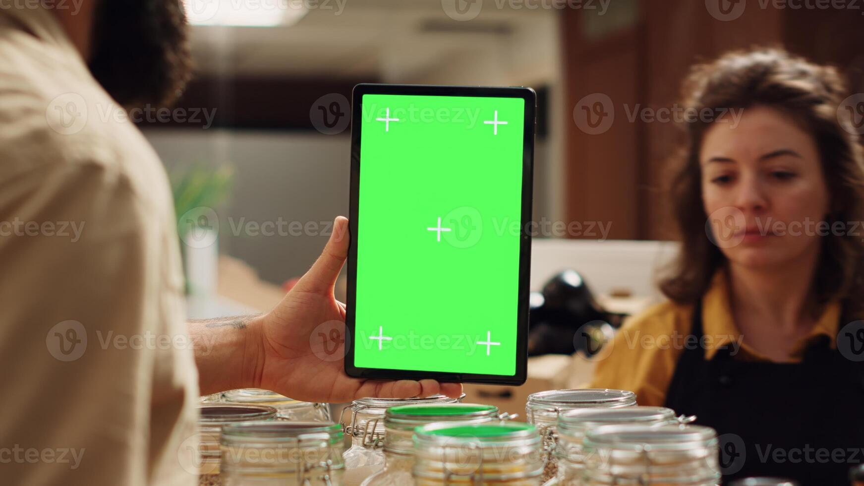 Customer uses mockup tablet in zero waste supermarket to check ingredients for healthy recipe, close up. Client in eco bio local shop with green screen device while shopping for pantry staples photo