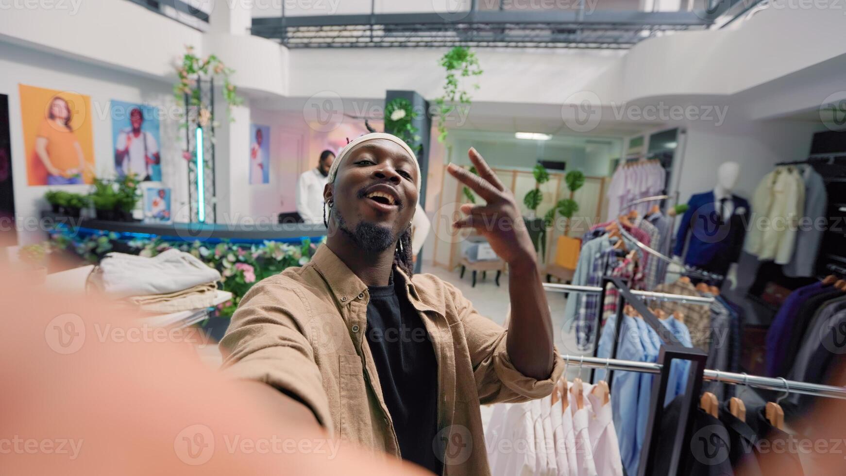 Man filming POV vlog while doing shopping in elegant fashion boutique, giving viewers info. Influencer doing social media content in clothing store, promoting clothing store new collection stock photo