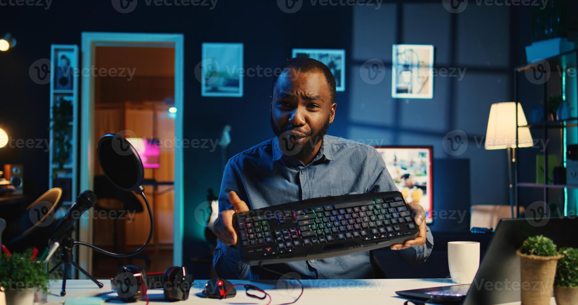 African american technology online star filming review of newly released wired gaming mouse, keyboard and headphones, giving viewership feedback and presenting specifications photo