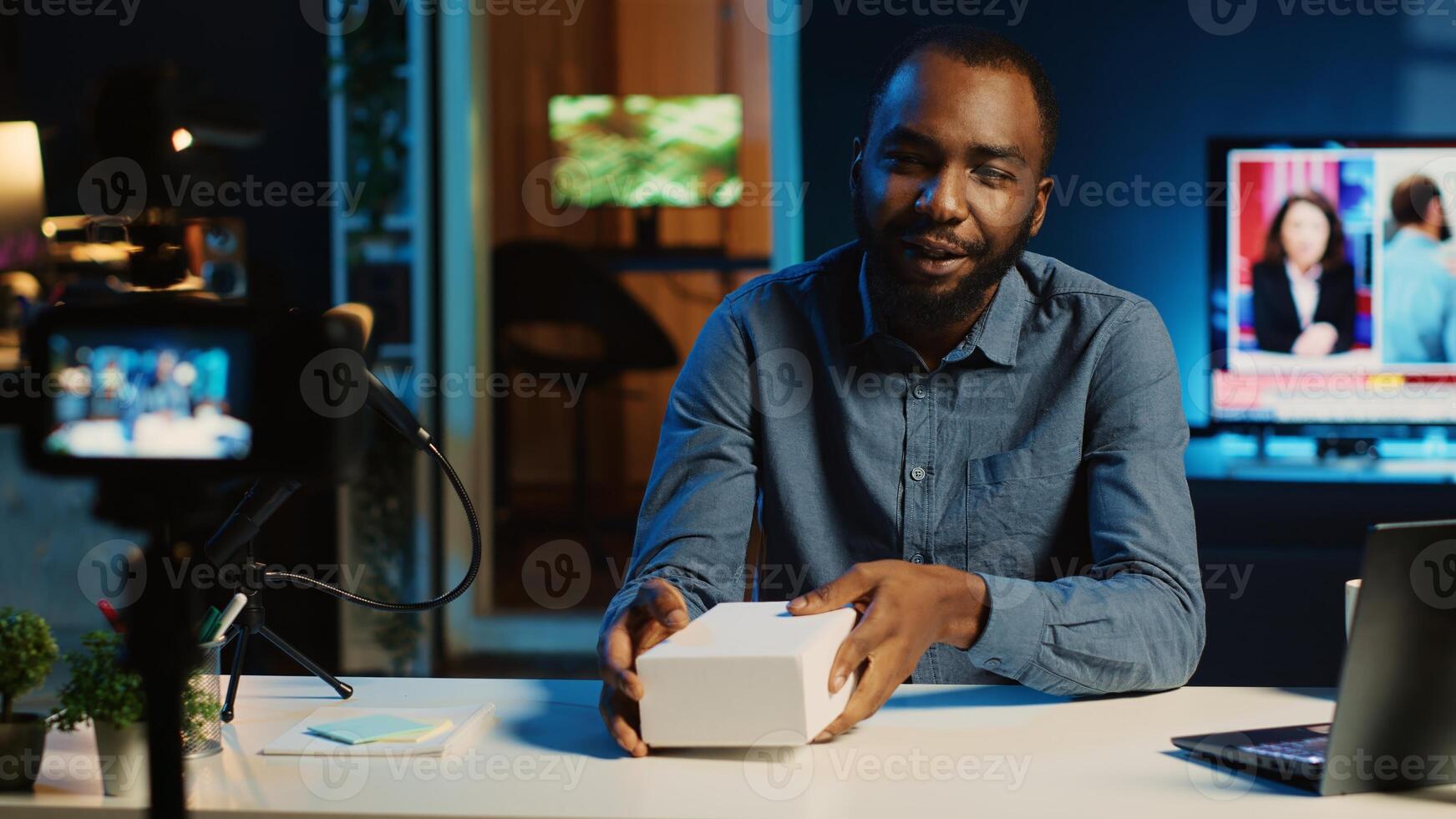 BIPOC tech content creator filming product unboxing of newly released smartphone, urging audience to purchase it too. Internet star payed by sponsor to show phone to subscribers photo