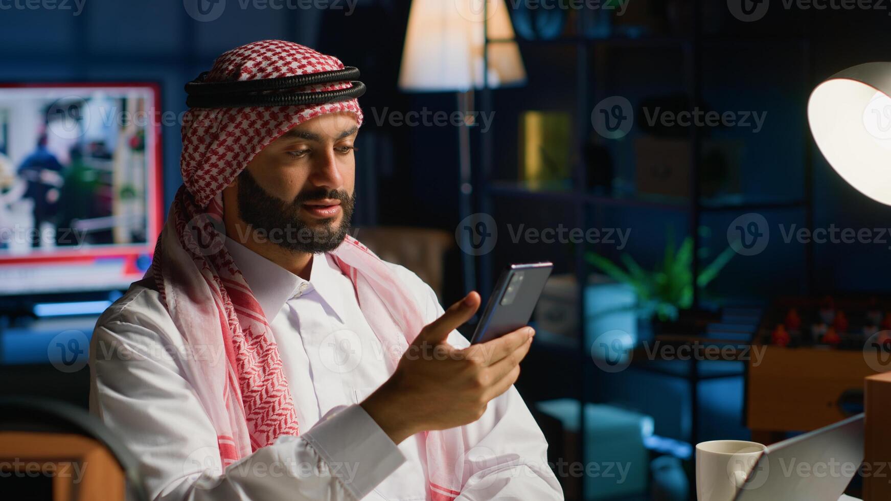 Arab man checking up on close friend during conference meeting over the phone. Middle Eastern person enjoying time together with friend in online call session using smartphone photo