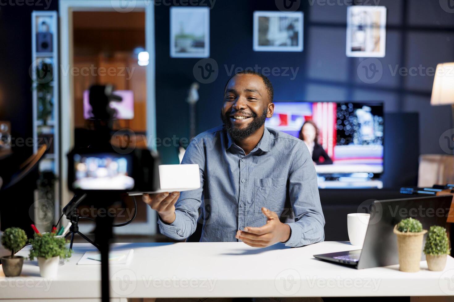 Smiling content creator at home with product waiting to be unboxed in front of him while he does introduction. Trending influencer doing unboxing footage for viewers photo
