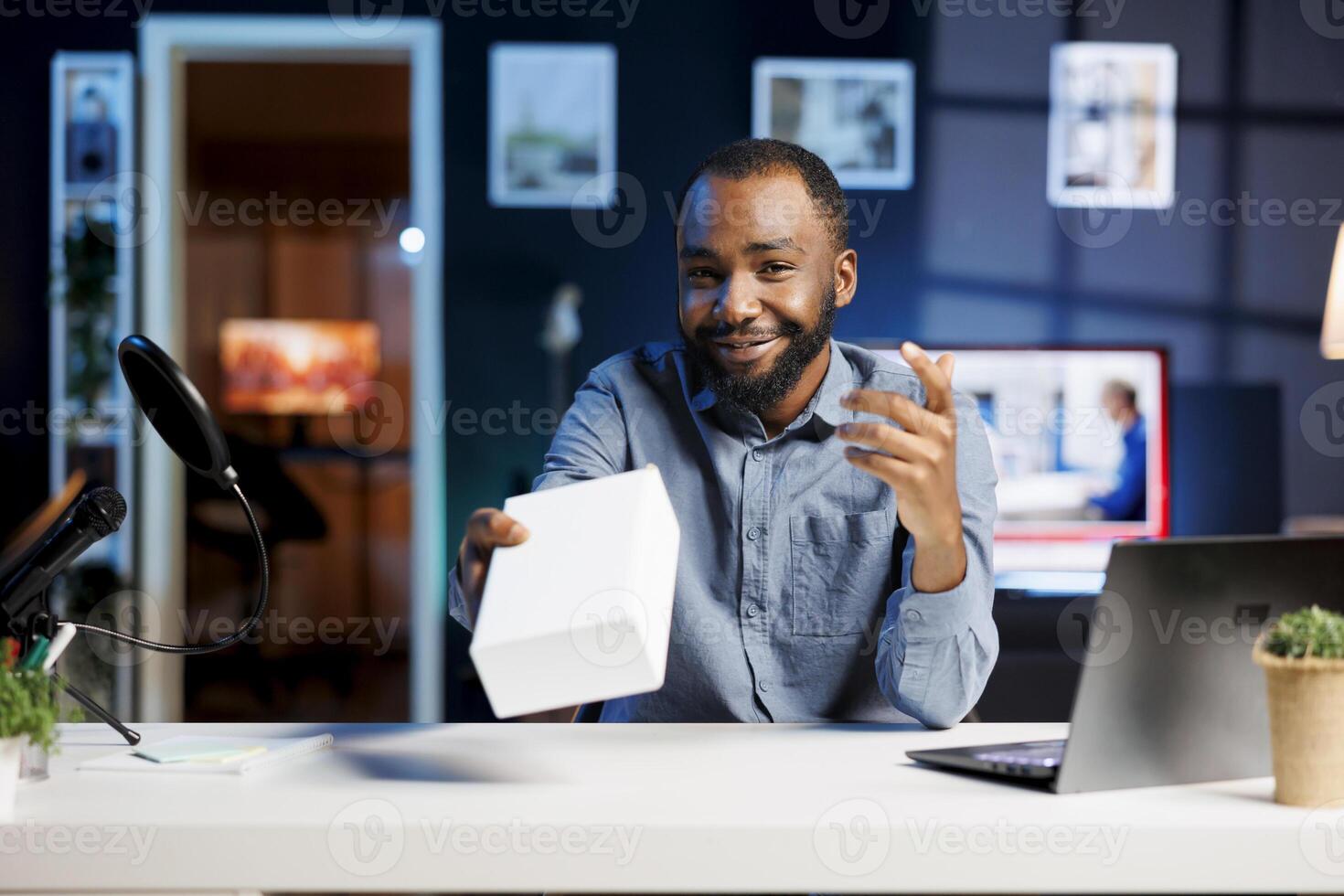 BIPOC tech content creator filming technology review of newly launched digital device, unboxing it and presenting specifications to audience. Influencer showing product to viewers photo