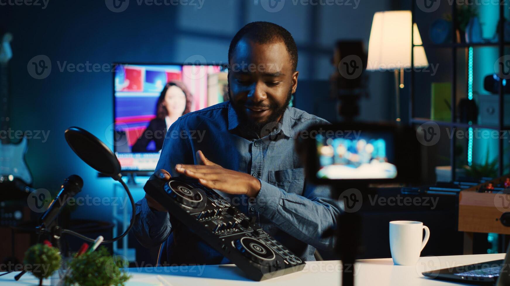 BIPOC content creator filming technology review of newly released DJ controller, unpacking it and presenting specifications to audience. Influencer showing sound mixer to fans photo