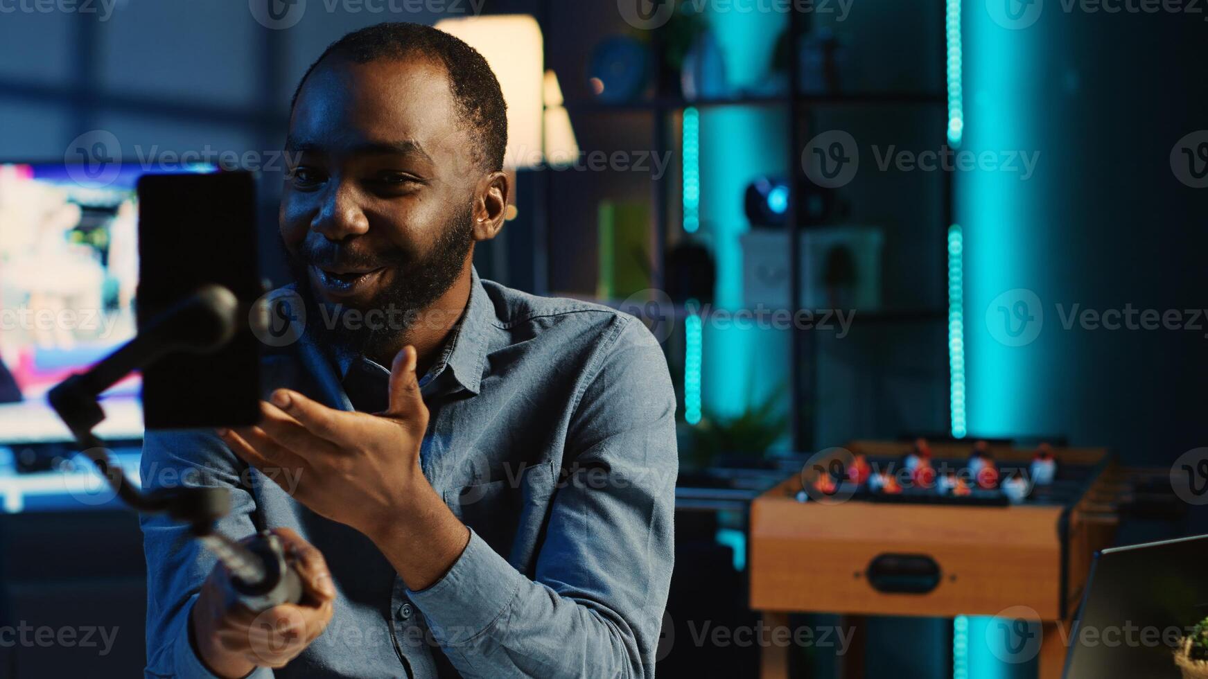 Content creator using selfie stick for smartphone, doing live broadcast for subscribers showing his new home studio design. Media star films himself for audience using mobile phone camera photo