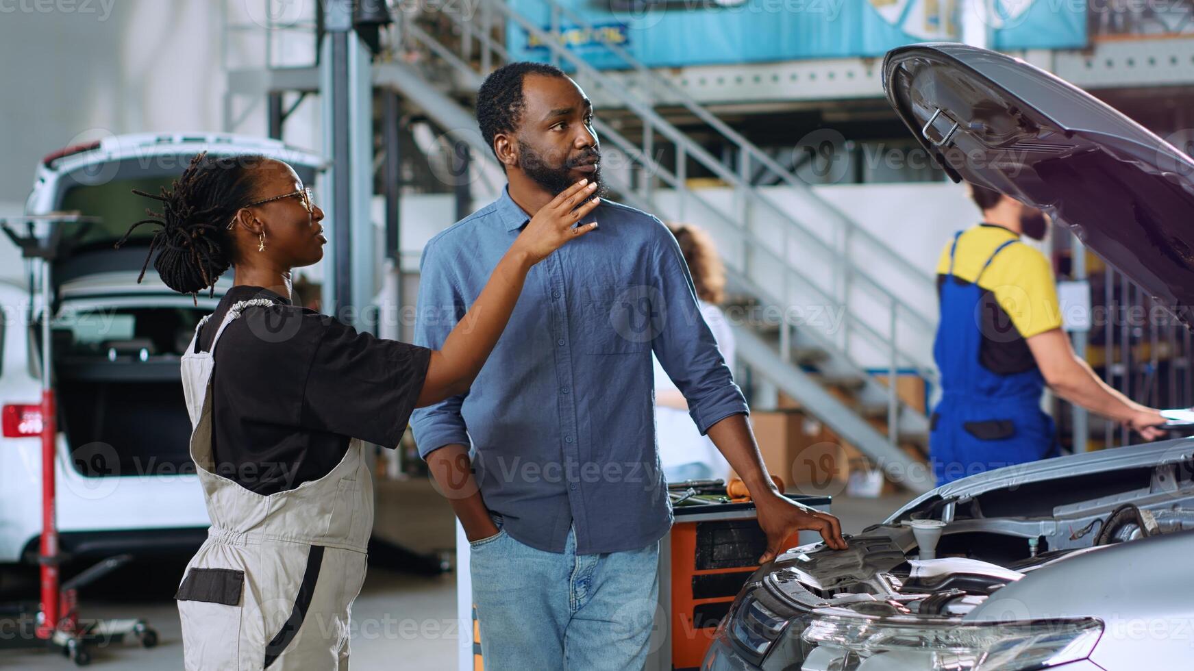 Mechanic in auto repair shop using augmented reality hologram to visualize car components to client. Expert using AR holographic technology to show customer vehicle repairments to be done photo