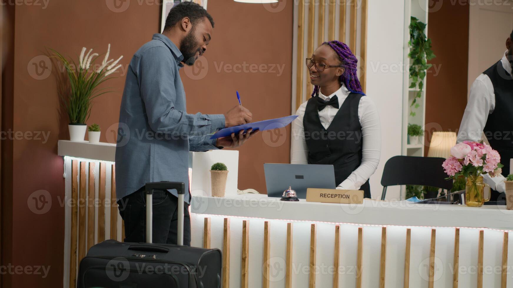 Guest filling in registration forms and signing papers before seeing room, finishing with check in. Employee providing luxurious concierge services, greeting people at front desk. Handheld shot. photo