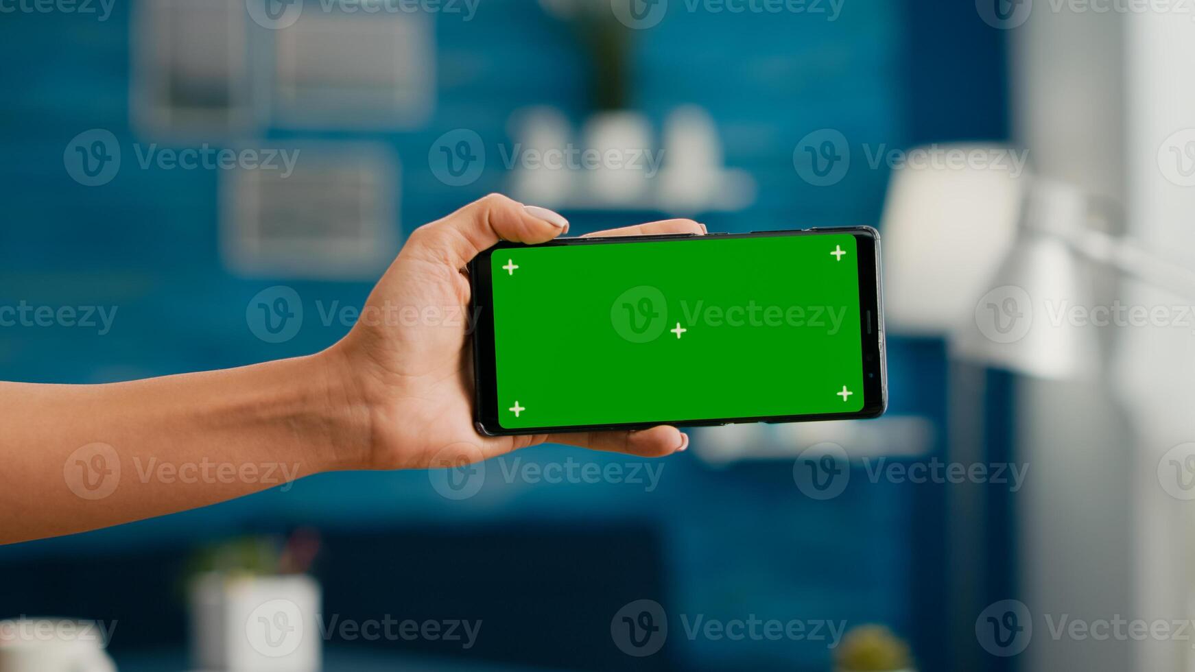 Close up of woman hands holding horizontal mock up green screen chroma key smartphone. Business woman using isolated phone for browsing social networks sitting on office desk photo