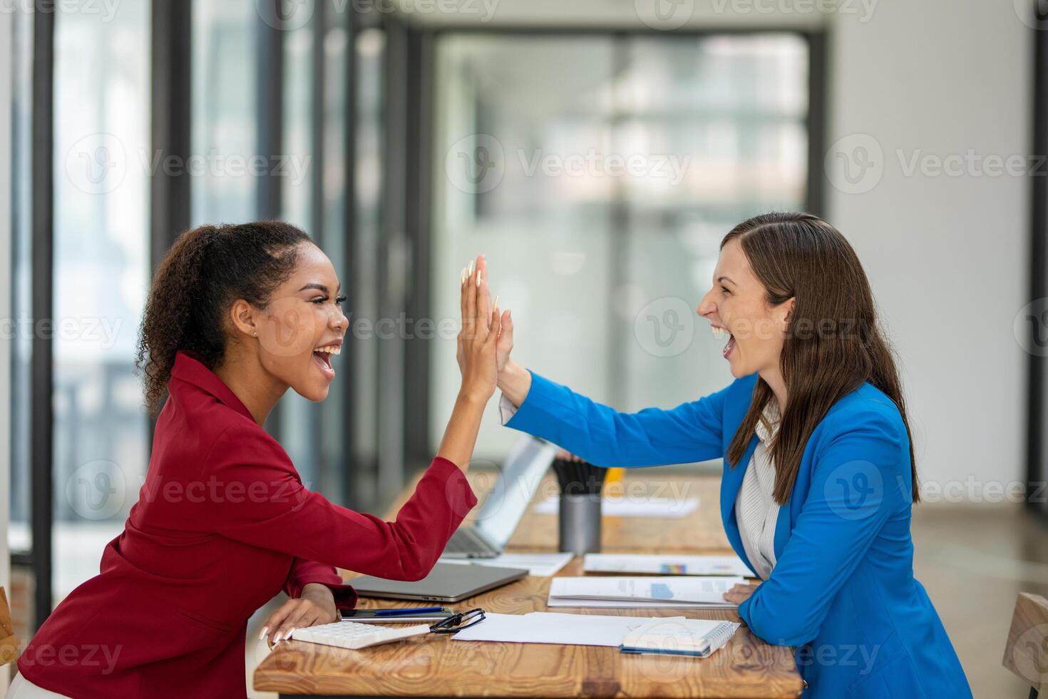 Two happy female coworkers giving a high five, celebrating a successful project or collaboration at their workplace. photo
