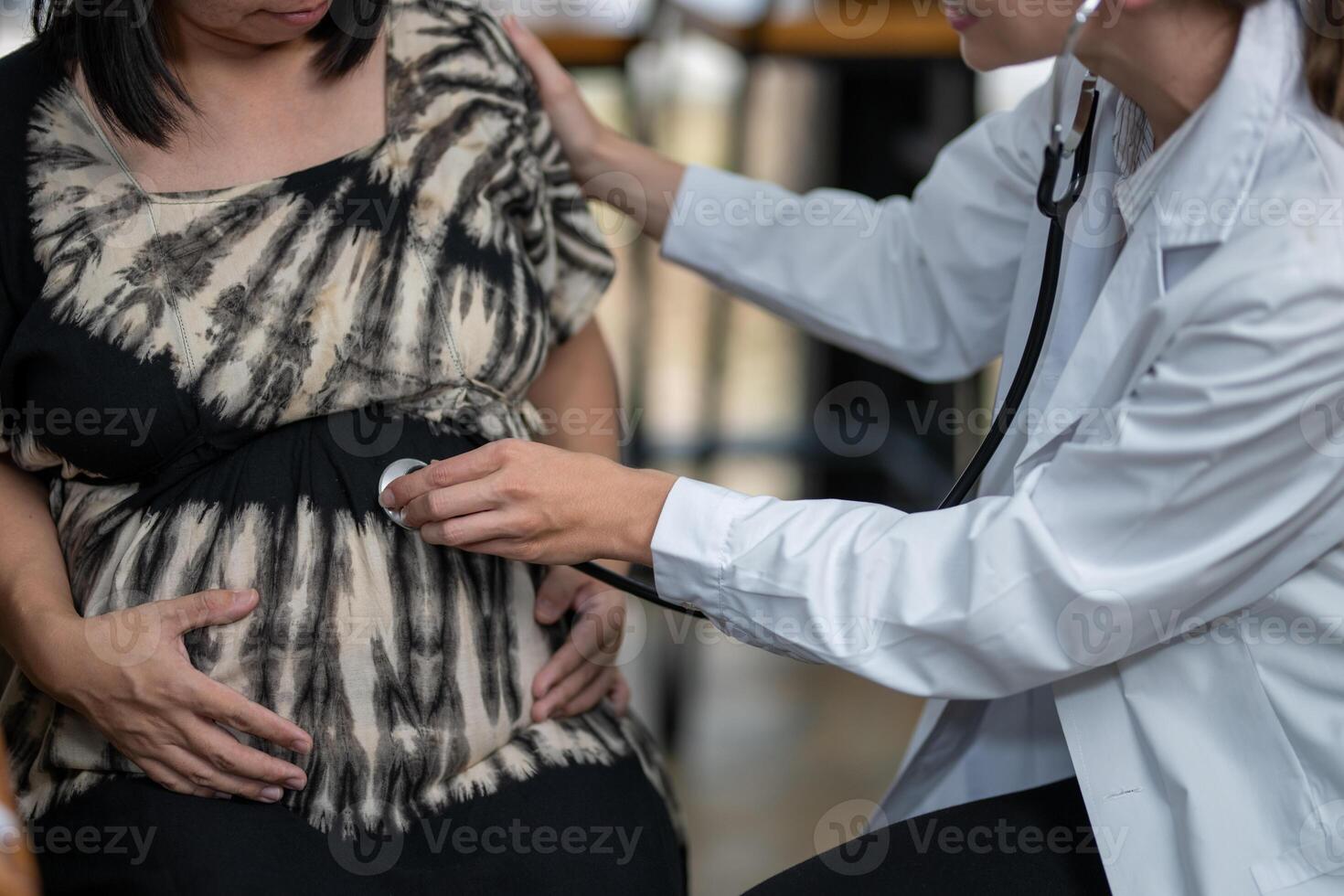 A doctor consults a pregnant patient, taking notes while discussing her symptoms and well-being during a prenatal visit. photo