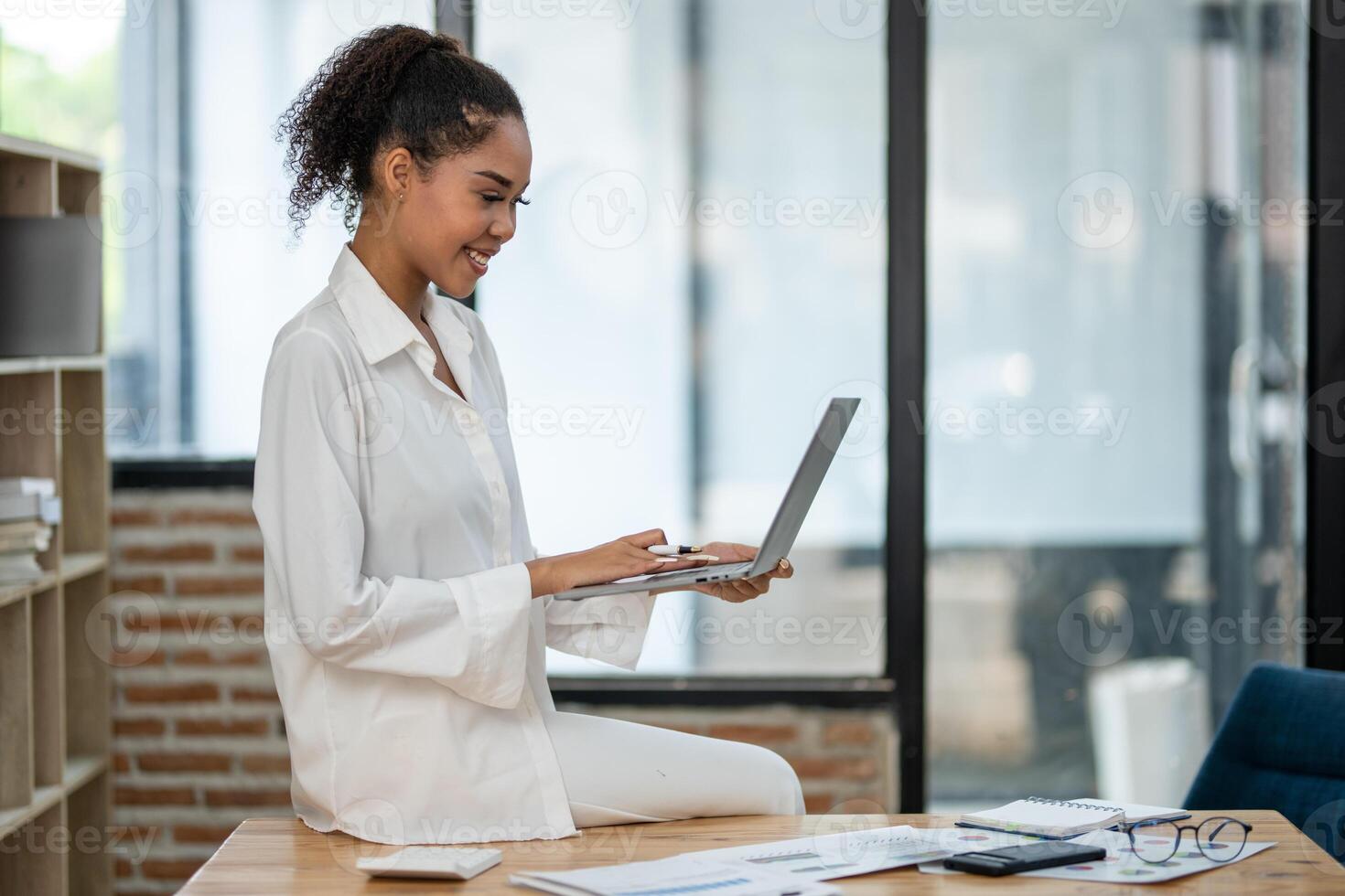 Confident female entrepreneur conducting financial analysis on her laptop in a well-lit office space. photo