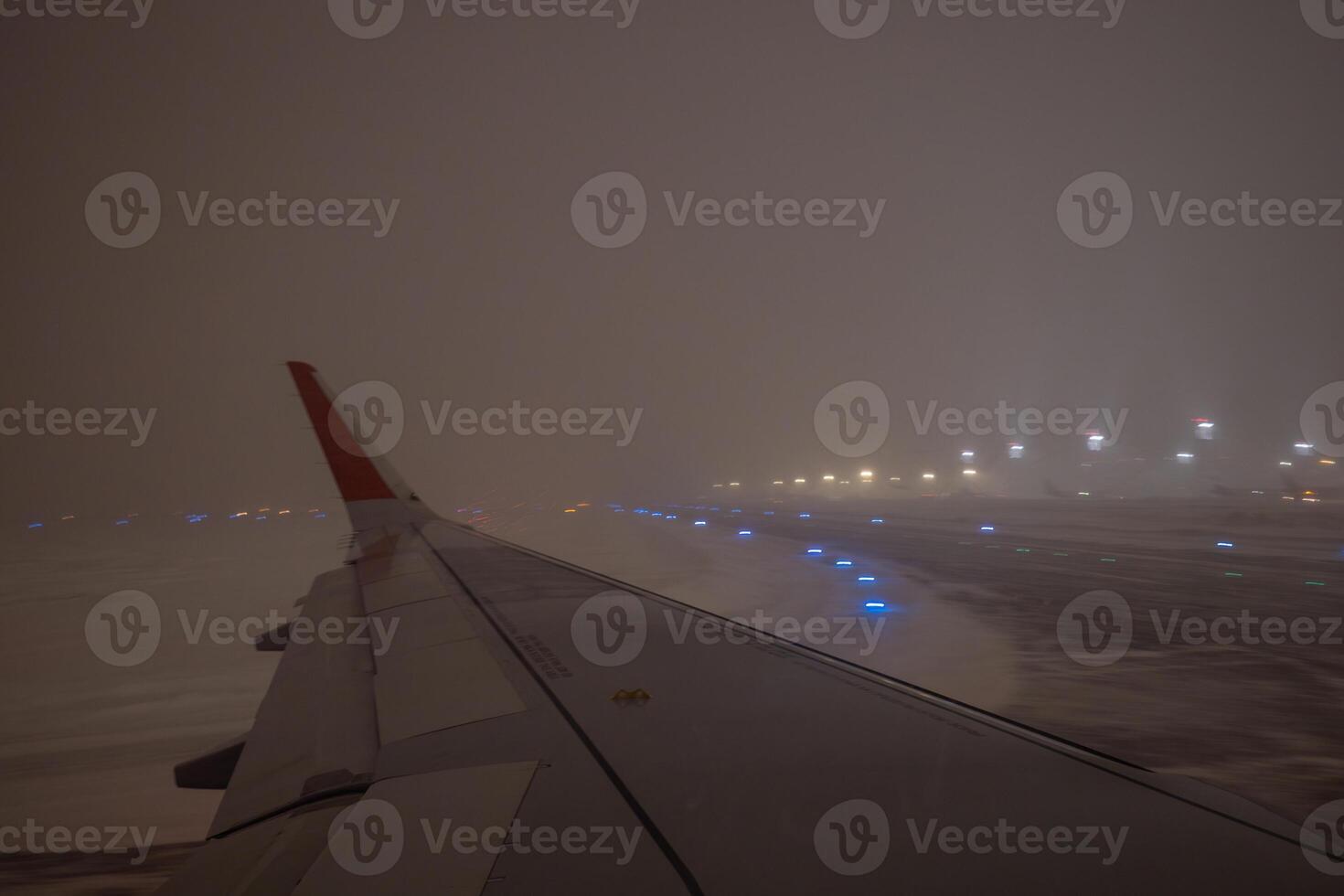 Airplane taxiing on runway during snow storm at night photo