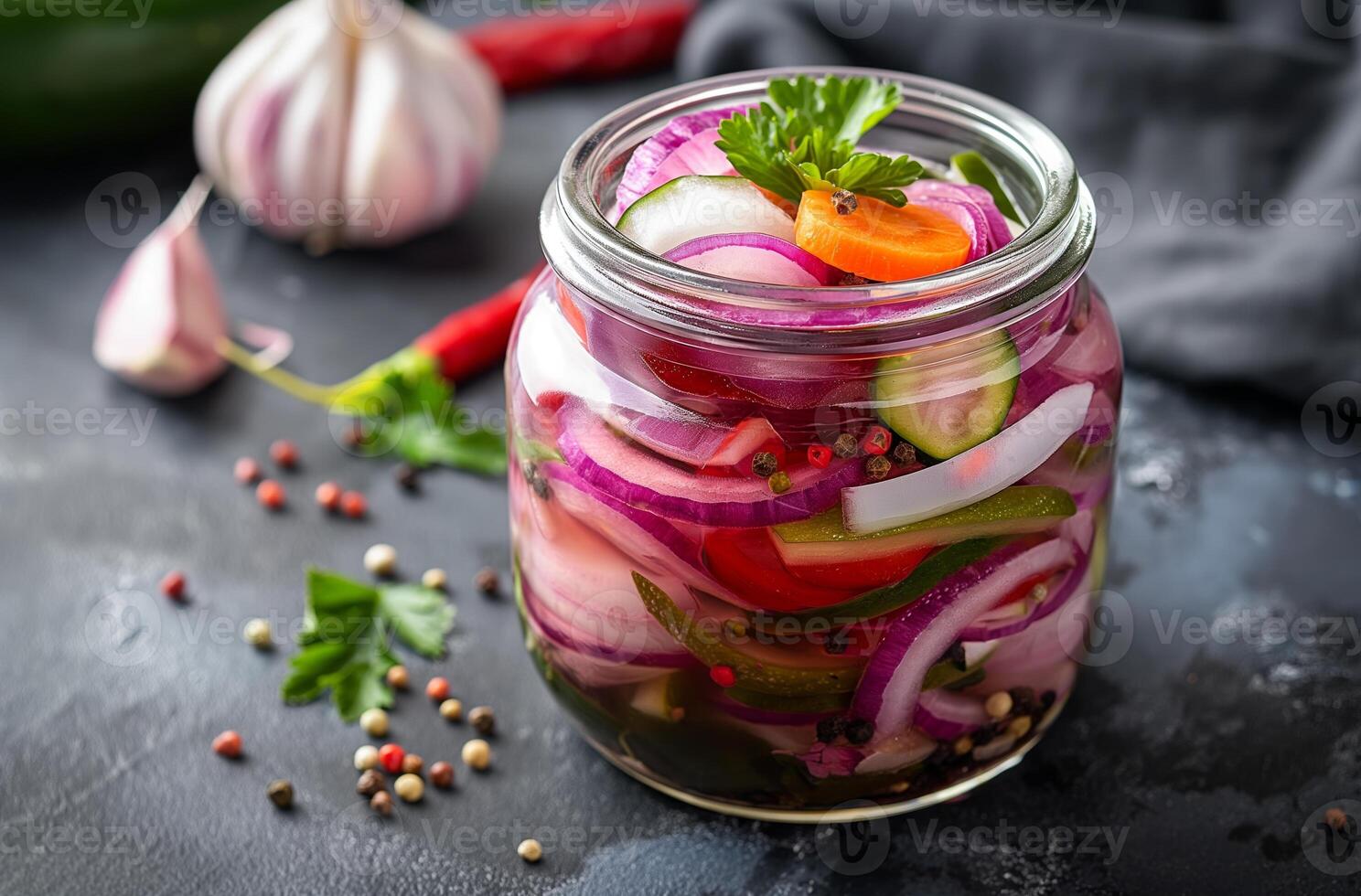Pickled vegetables with red onions, cucumbers, carrots, garlic, and peppercorns in glass jar photo