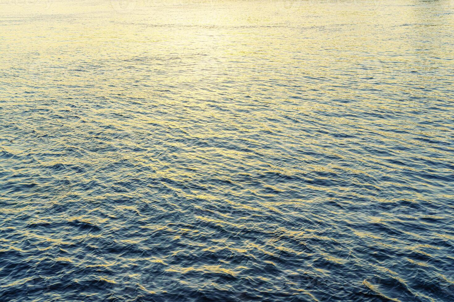 The texture of ripples on the water in a pond illuminated by the setting sun. Natural background. photo