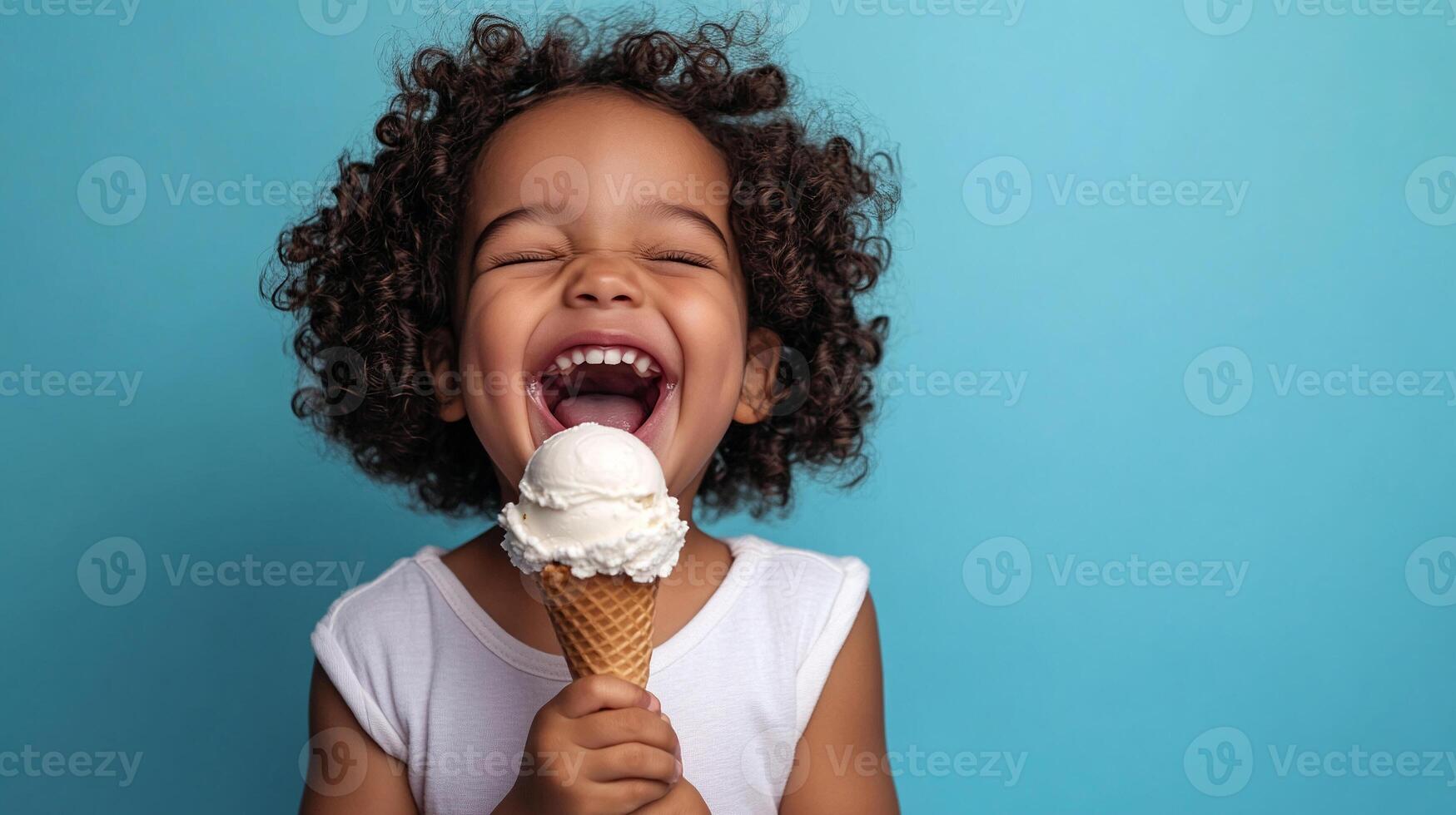 A little girl with curly hair is eating an ice cream cone photo
