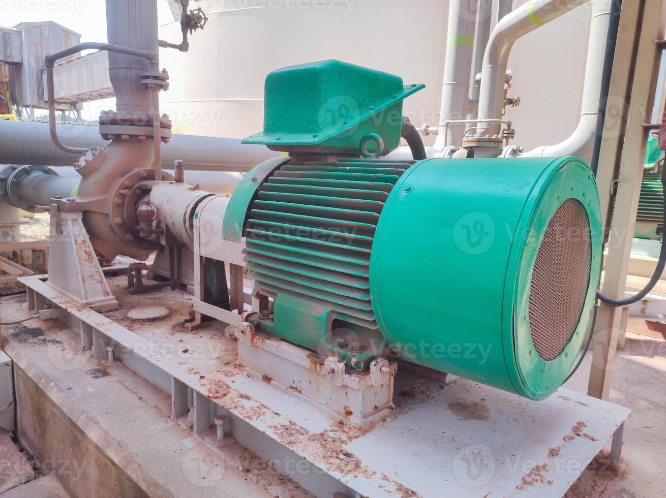 A green and white pump sitting on top of a metal pipe photo