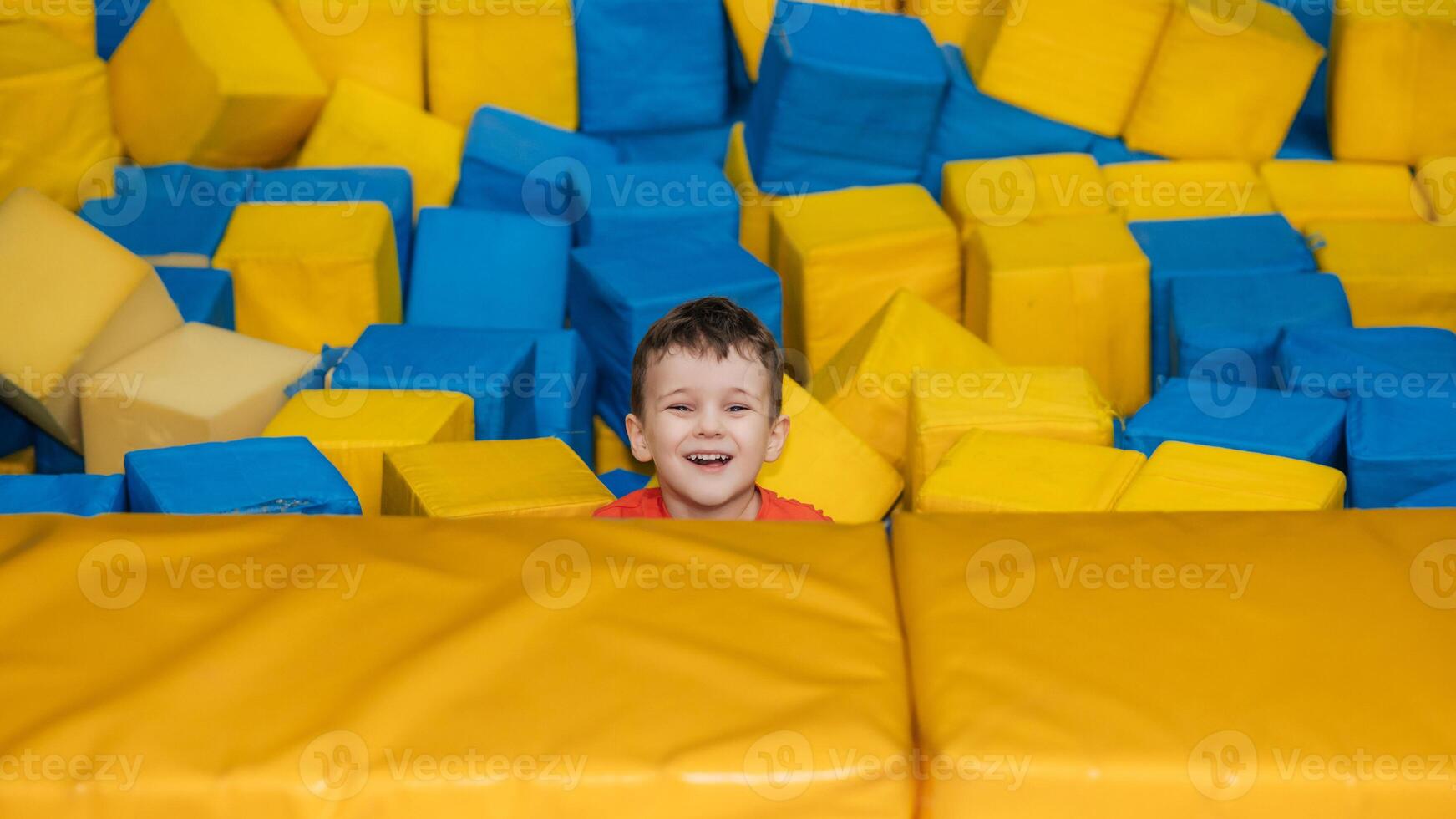 A boy child plays in a pool with soft cubes,. A child in a game entertainment children's room. photo