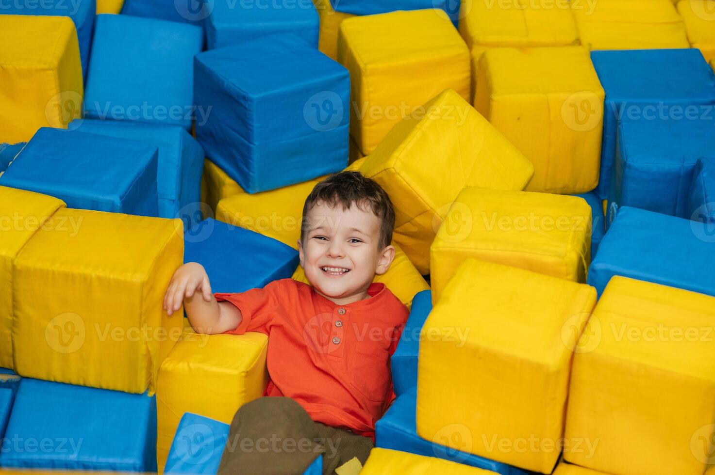 A boy child plays in a pool with soft cubes,. A child in a game entertainment children's room. photo