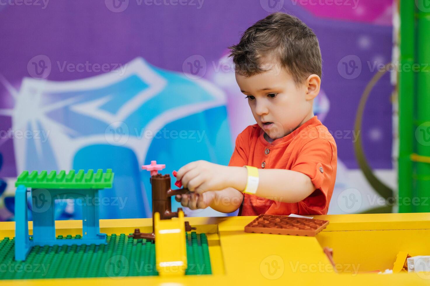 Close-up of a boy's child playing with colorful plastic bricks at a table. The kid has fun and builds from bright constructor cubes. Early learning. Educational toys photo