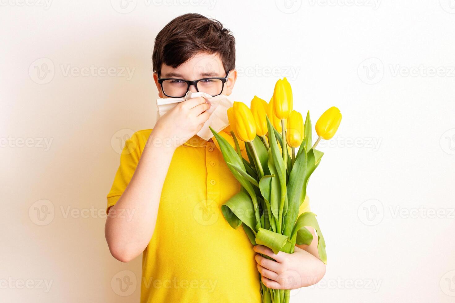 a boy with a bouquet tulips, covered his nose with a paper napkin and sneezes photo