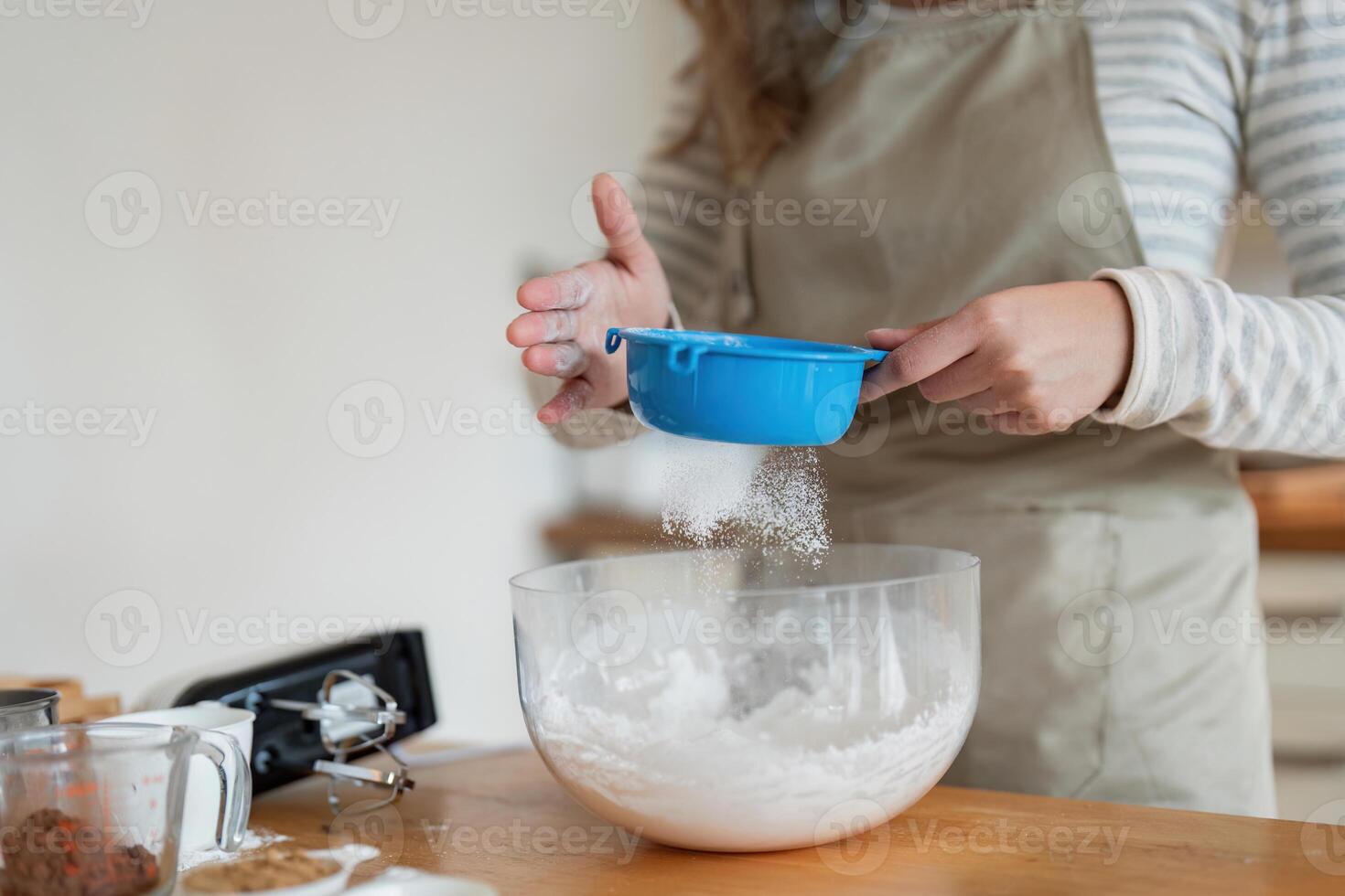 Woman Adding Flour to Mixing Bowl for Baking in Kitchen photo