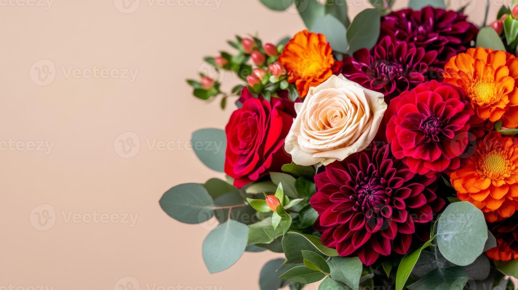 Close up of an elegant autumn bouquet with deep red roses burgundy dahlias and orange marigolds accented with dark green foliage and eucalyptus isolated on a neutral background photo