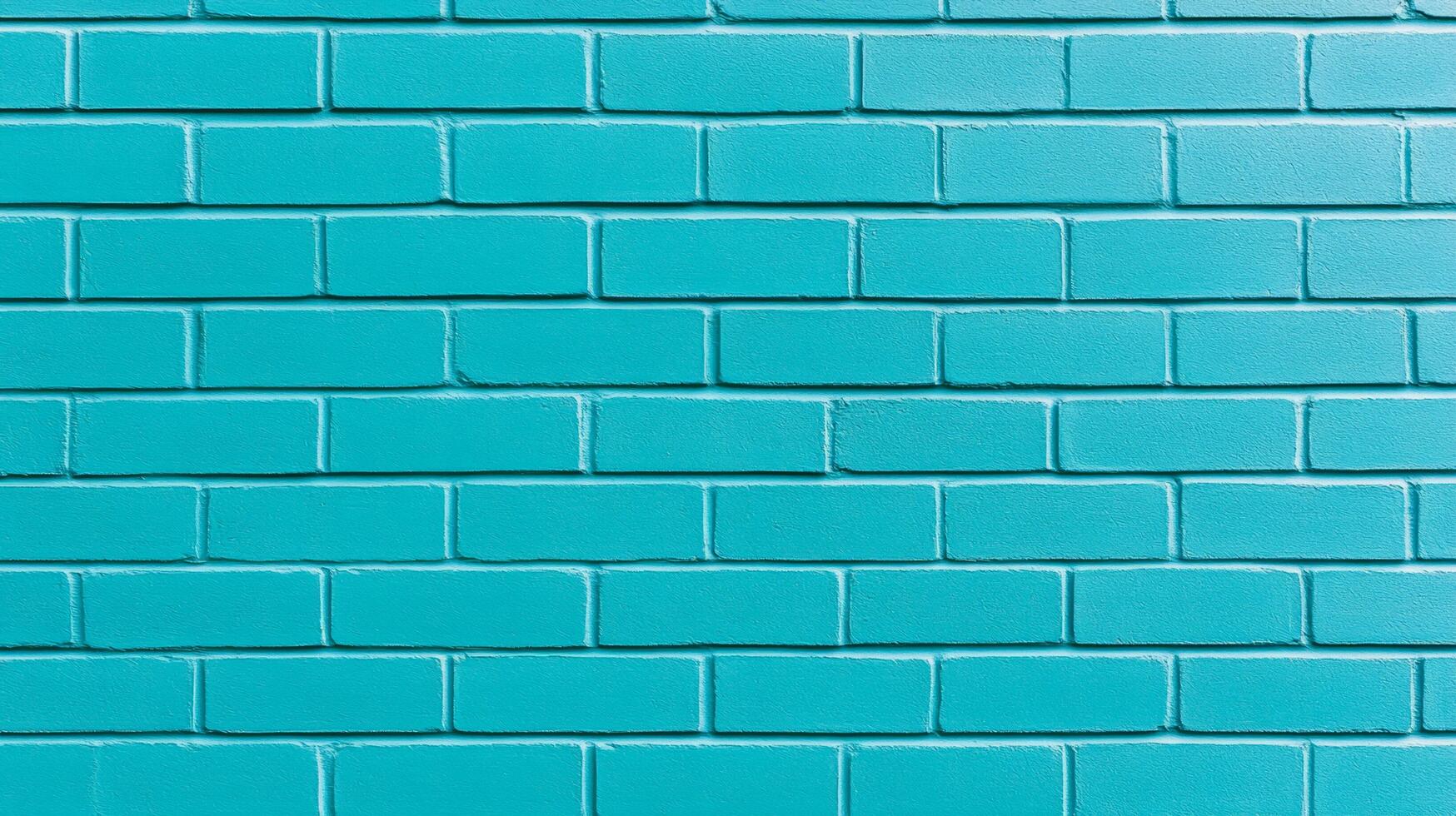 Closeup of a textured painted brick wall in vibrant turquoise showing rough brush strokes and slightly uneven coverage perfect for a bold and modern design aesthetic photo
