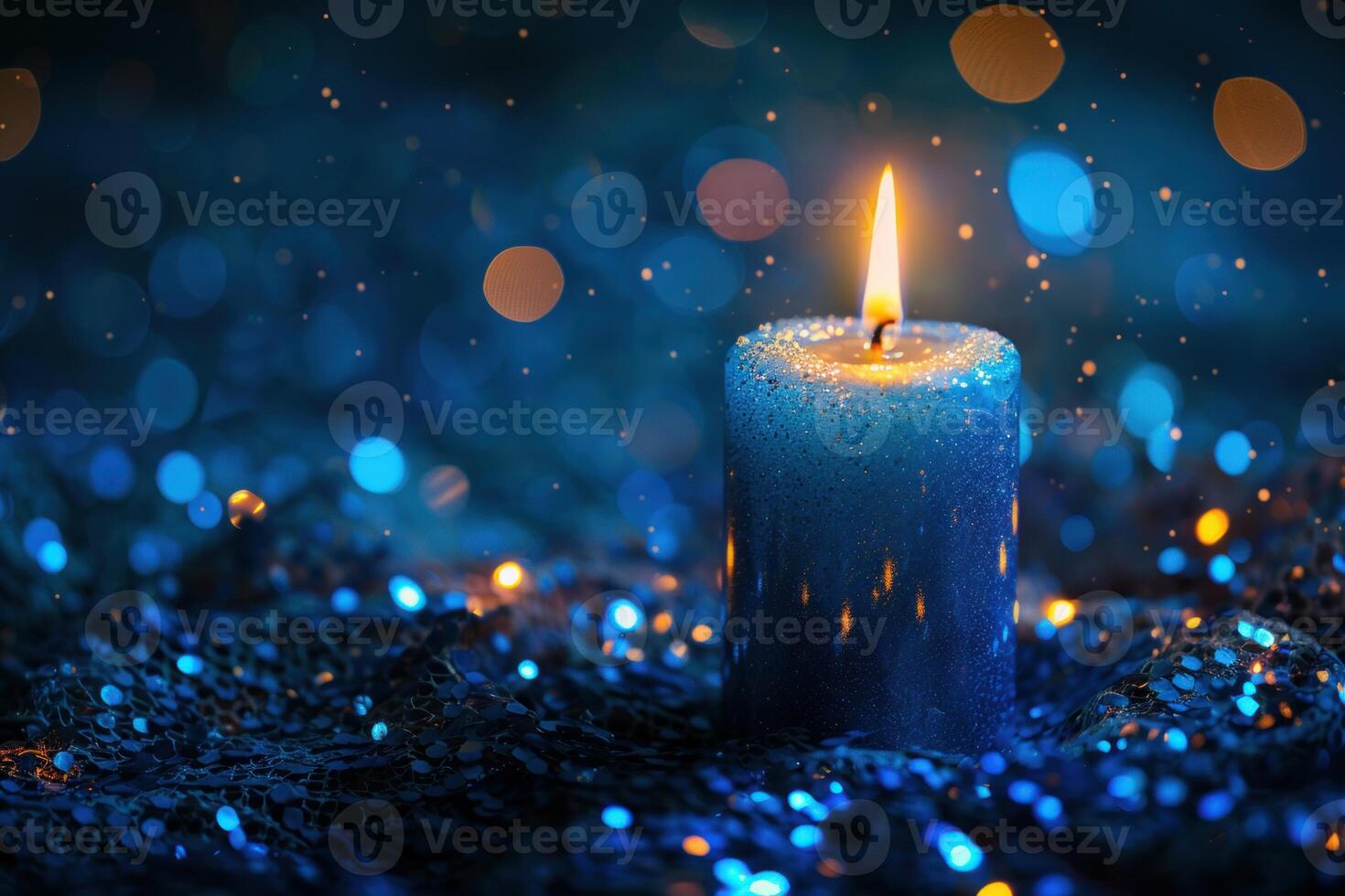 Blue candle burning on sparkling sequins creating magical bokeh photo