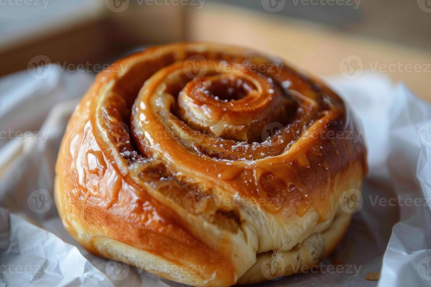 Delicious cinnamon roll drizzled with caramel lying on paper photo