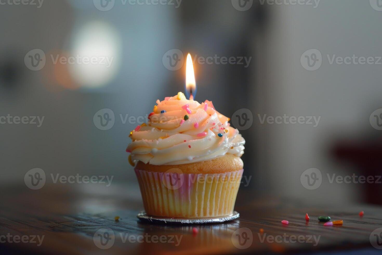 Delicious birthday cupcake with a lit candle on a wooden table photo