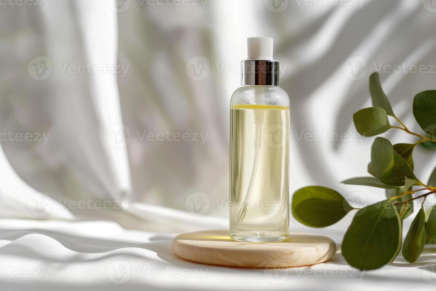 Transparent bottle of essential oil standing on wooden podium with eucalyptus photo