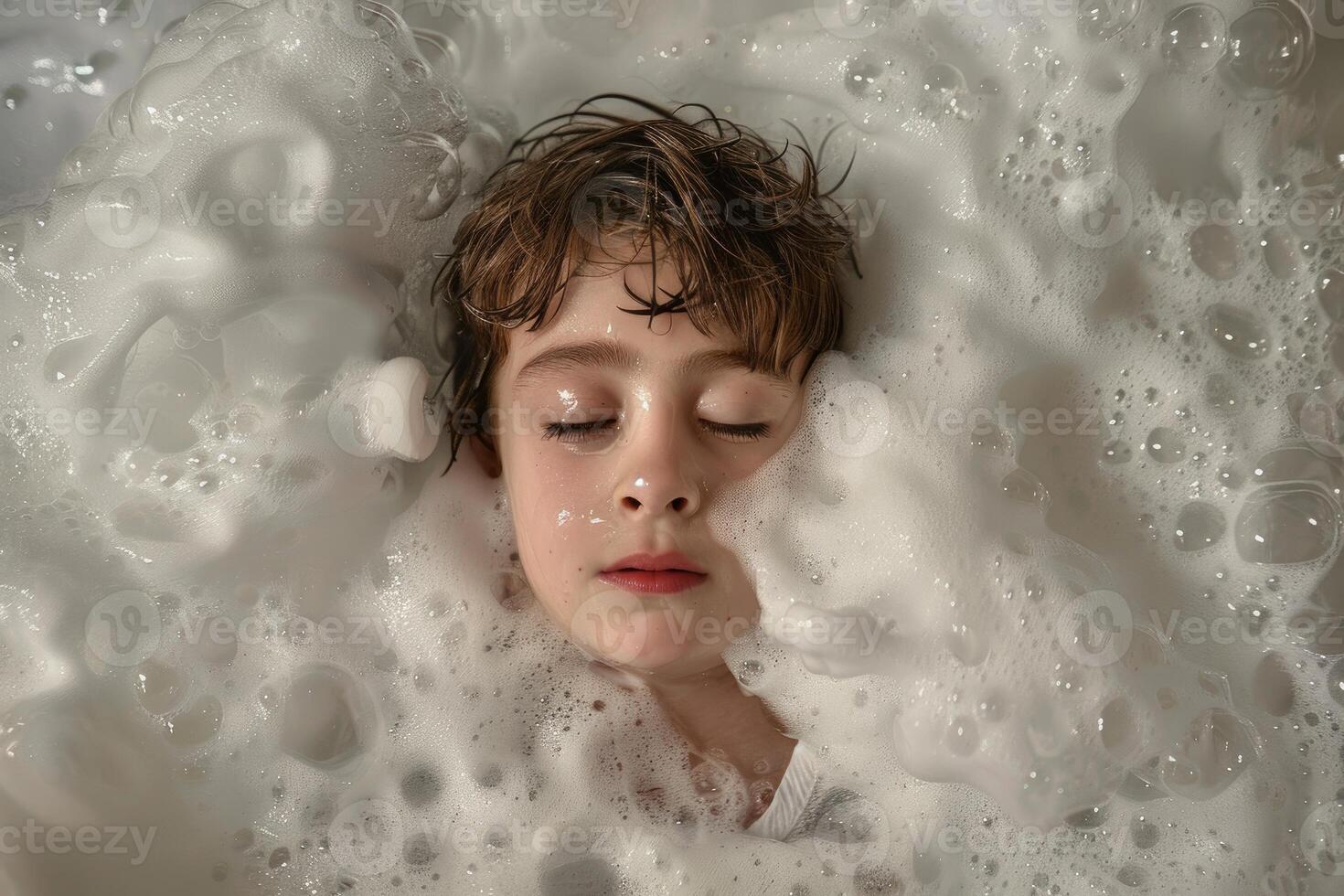 Young boy is having a relaxing bath full of soap bubbles photo