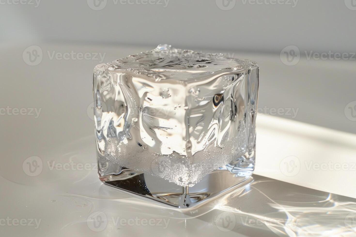 Single ice cube melting on white surface with bright sunlight photo