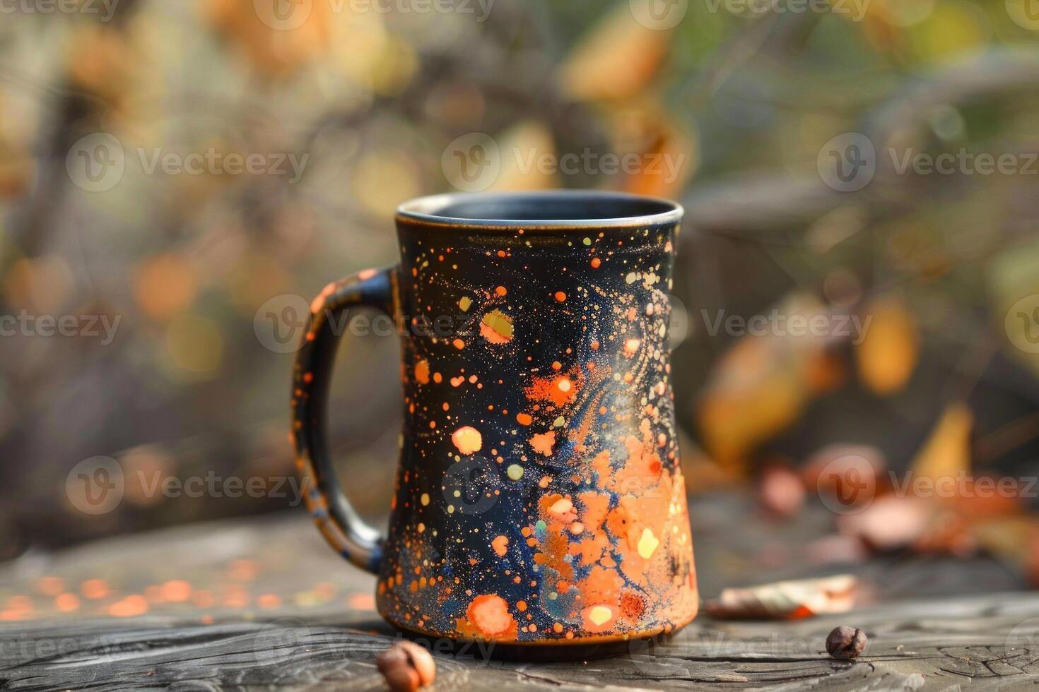 Black and orange splattered handmade ceramic coffee mug standing on rustic wooden surface photo