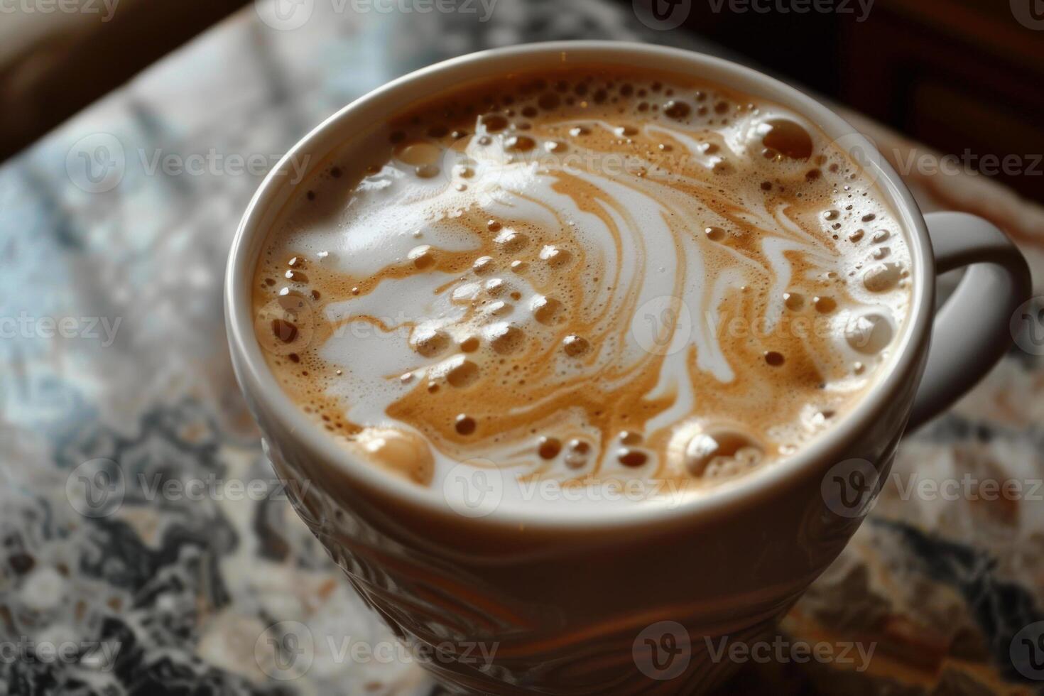 Steaming cup of coffee with latte art on foam sitting on patterned countertop photo
