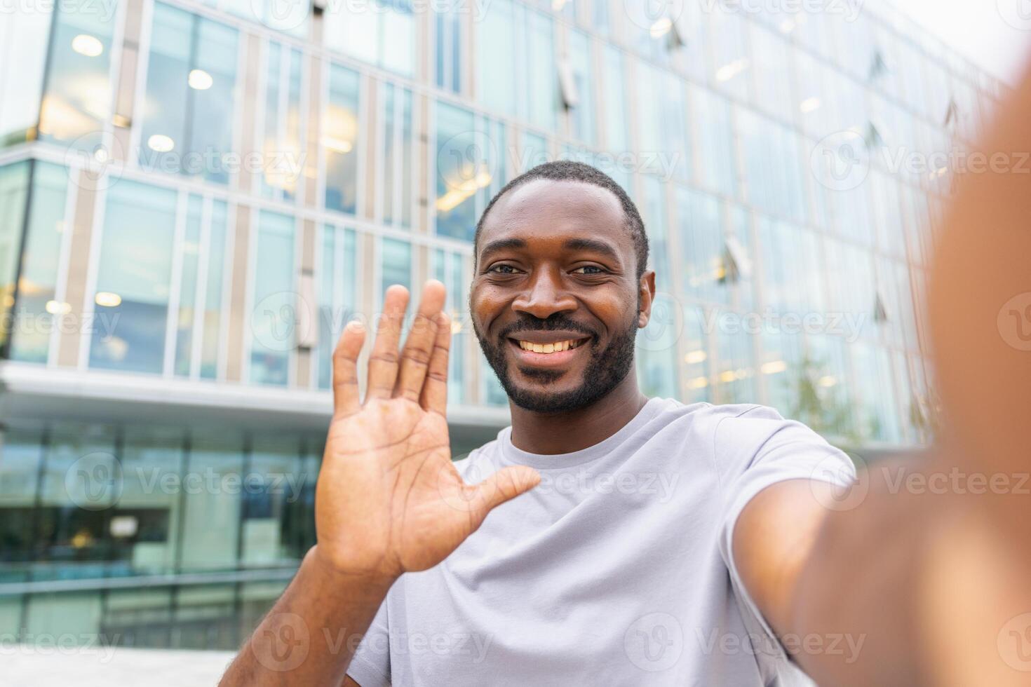 African American man with smartphone having call on street in city. Guy blogger streaming chatting in social network. Man having virtual meeting vlog online chat outdoor Selfie webcamera view photo