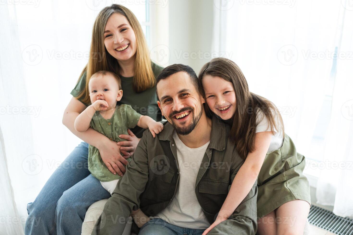 Happy family at home. Mother father two children daughters relaxing indoor. Mom dad parents baby girls kids relax playing having fun together. Family smiling laughing enjoying tender love moment photo