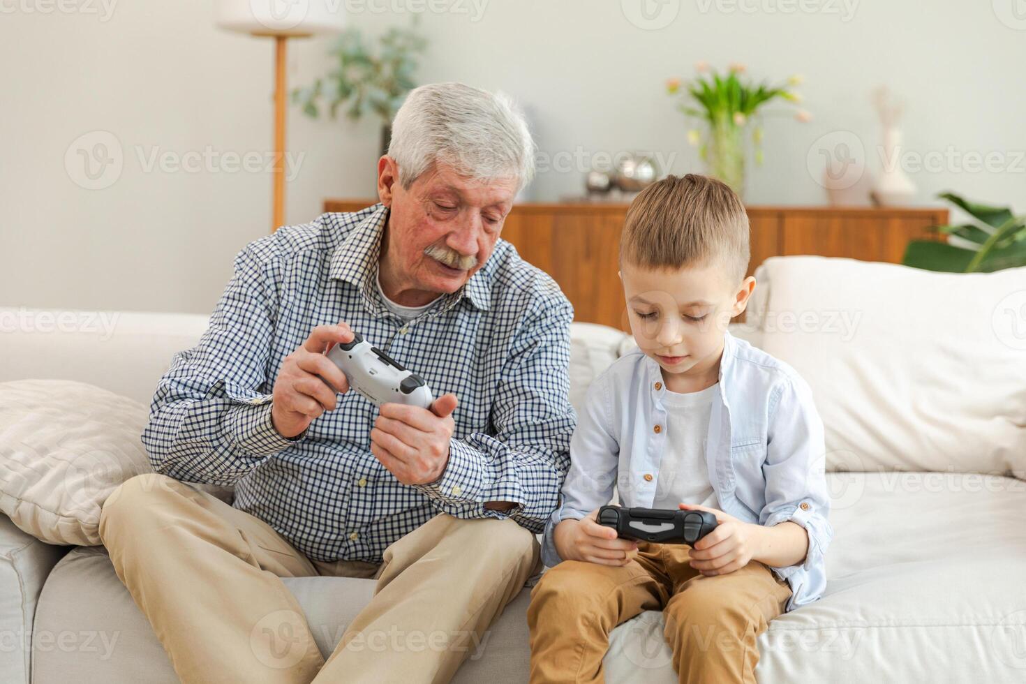 Happy family. Old senior man grandfather boy grandson playing game with joysticks at home. Smiling grandparent and child using gamepads for game. Older generation modern tech usage photo