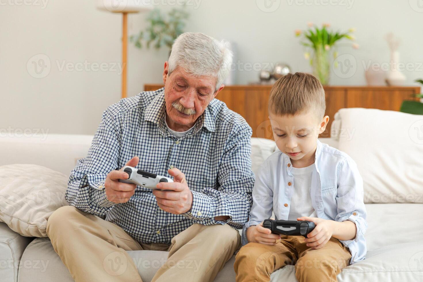 Happy family. Old senior man grandfather boy grandson playing game with joysticks at home. Smiling grandparent and child using gamepads for game. Older generation modern tech usage photo