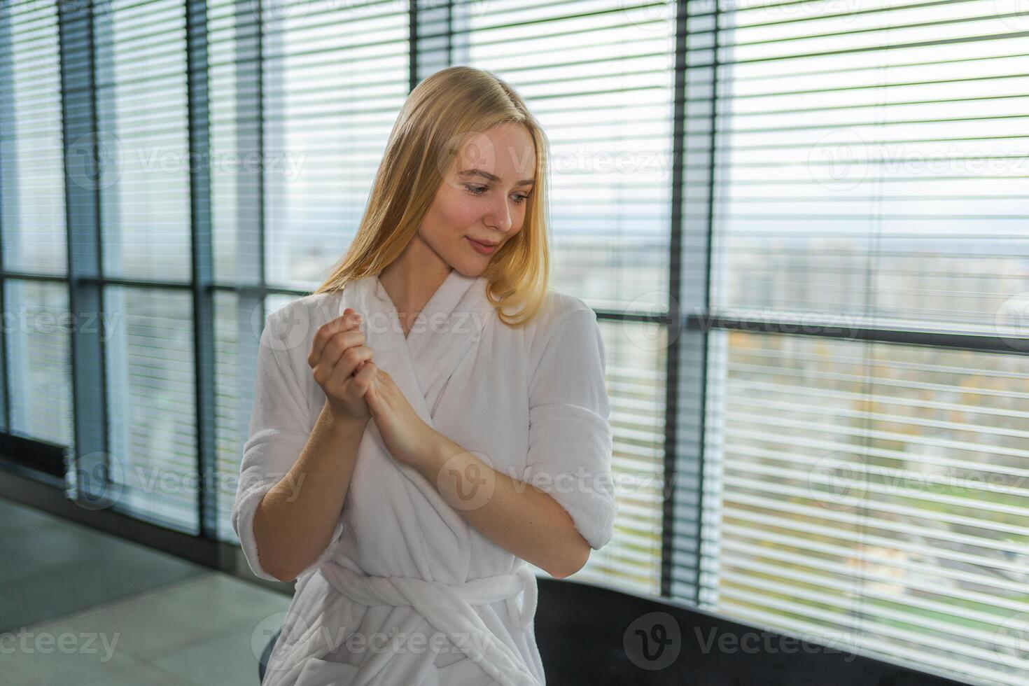 Woman applying moisturizing body lotion on hand arm relaxing in bathroom. Girl rubbing nourishing cream doing daily skincare routine spending morning in bathroom. Beauty treatment spa body skin care photo