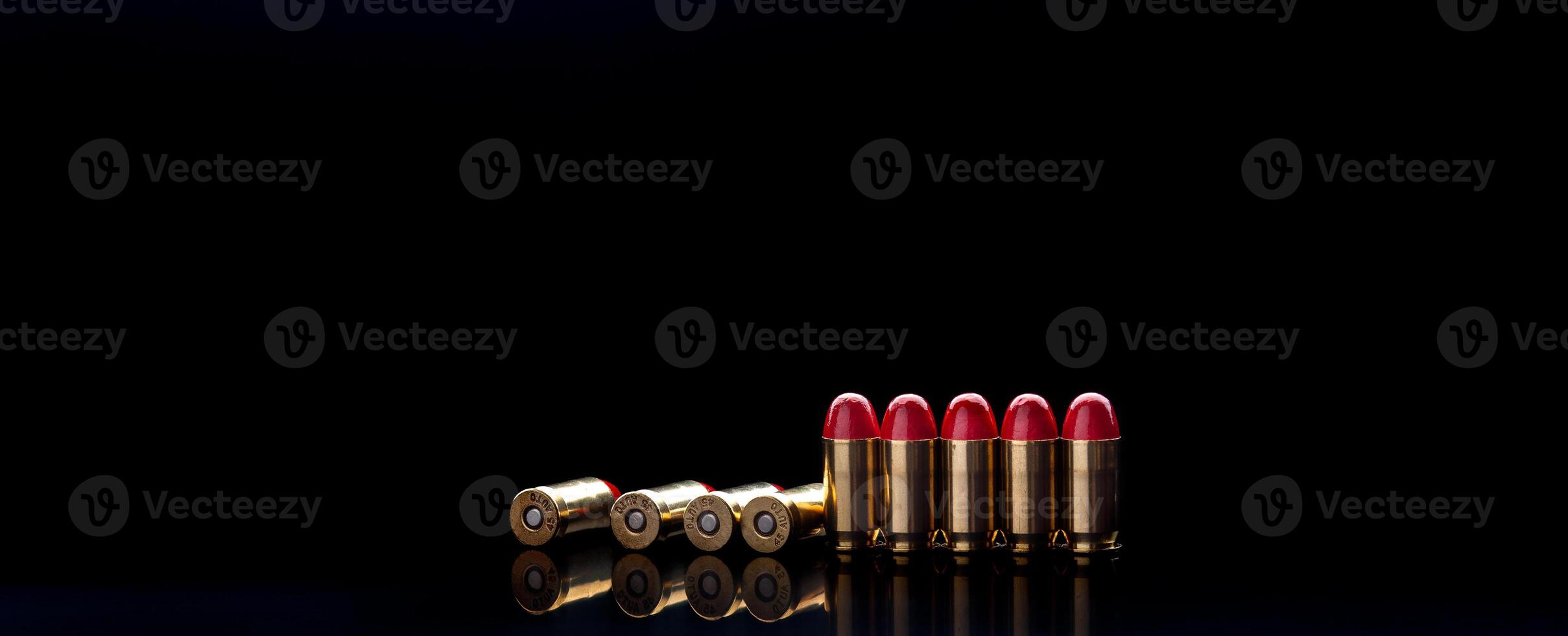 Pistol cartridges with red silicone coating. Bullets for a pistol on a dark back. Reflections on a black surface. photo