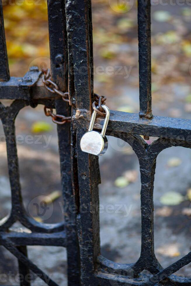 Antique lattice gates closed on a chain with a padlock. The passage is closed. photo