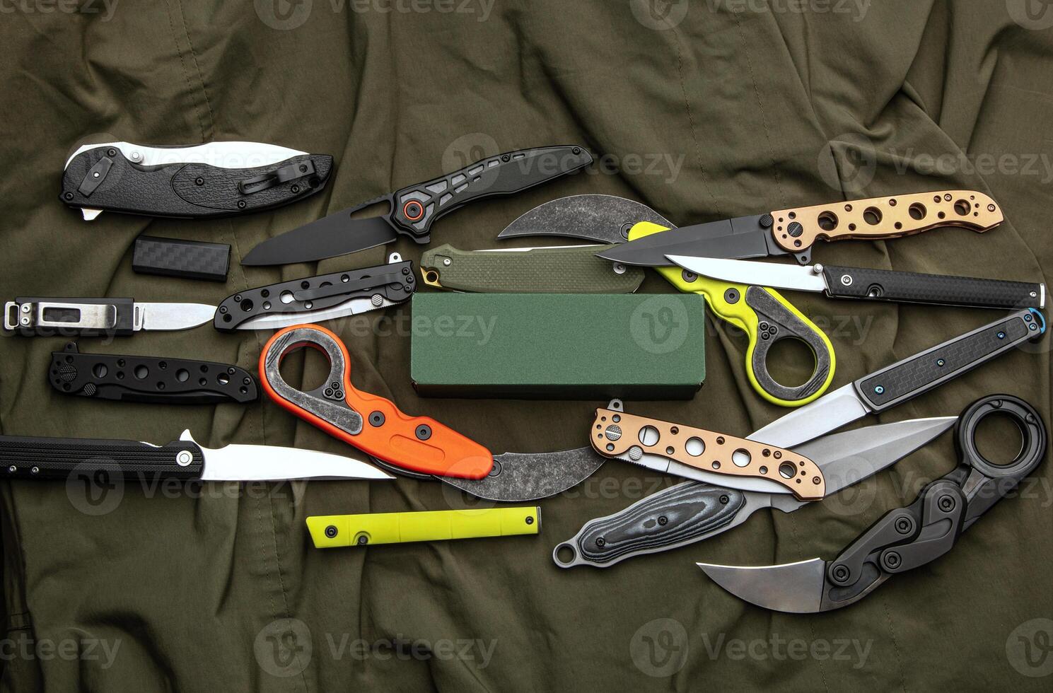 A variety of folding and pocket knives lie on khaki fabric. A versatile pocket tool and self-defense tool. photo