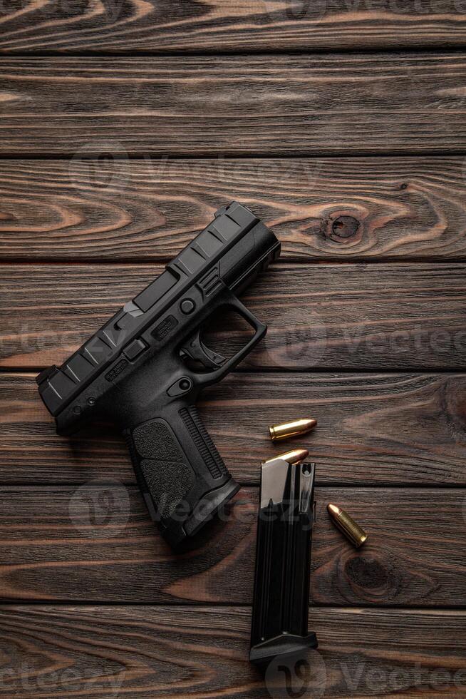 Pistol and cartridges for it on a wooden back. A short-barreled weapon for self-defense. photo