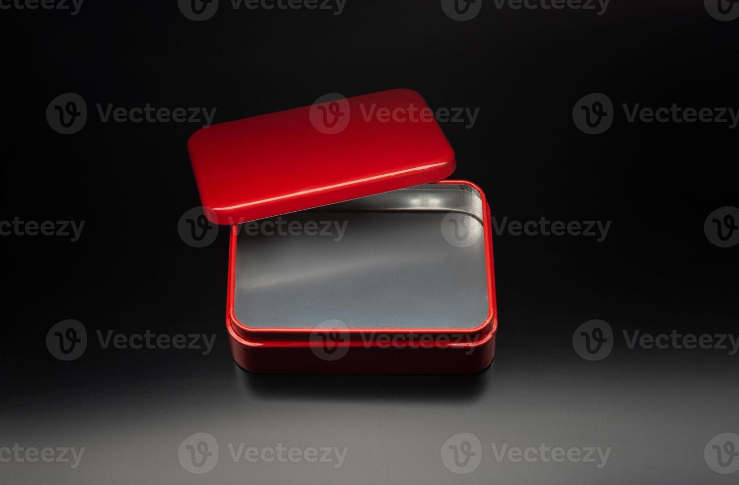 Red metal box of a rectangular background on a black gradient background. Mockup of bright packaging for a small gift. Dark back. photo