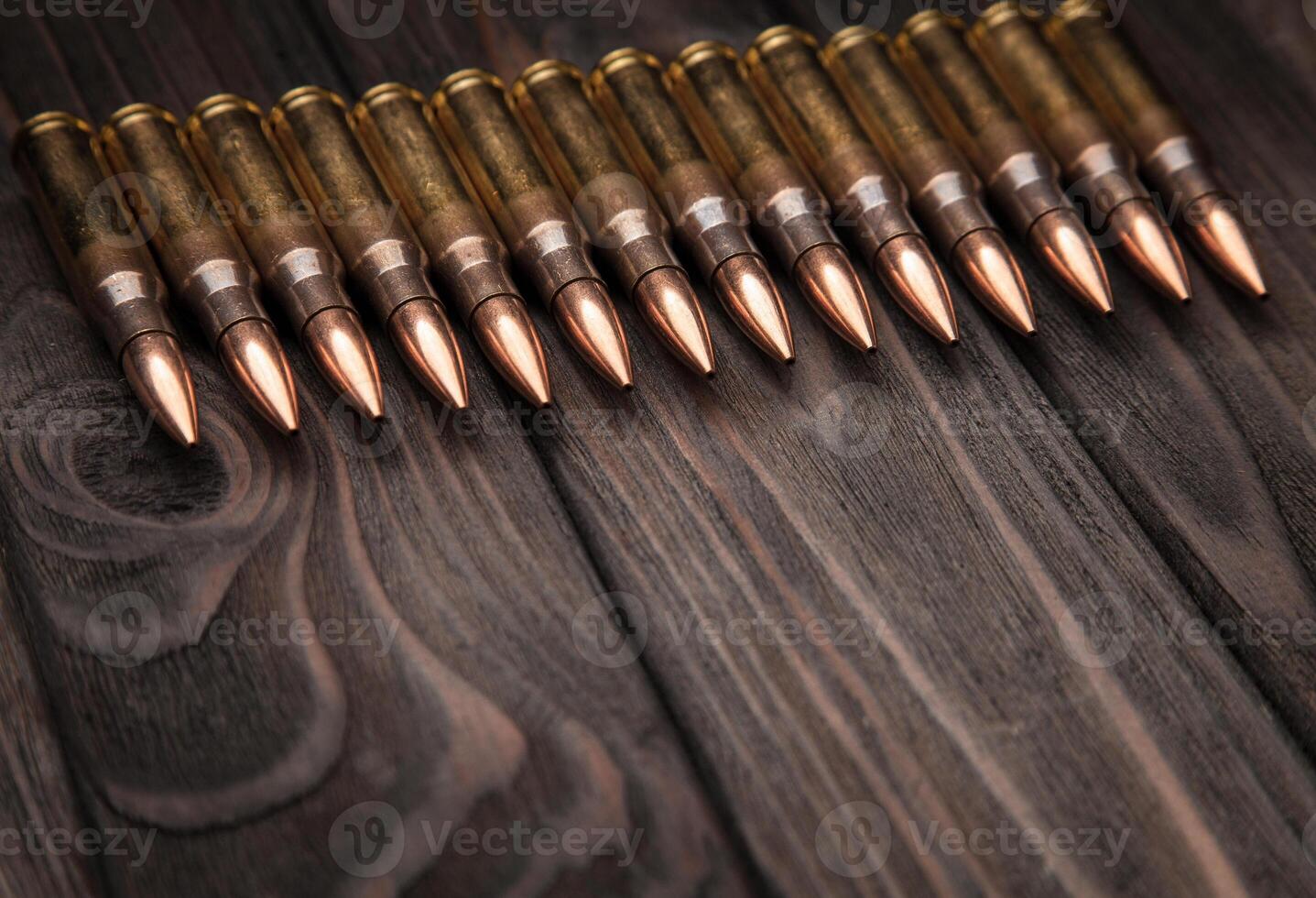 Rifle cartridges on brown wooden boards. The concept of gun postcards. Ammo on the table with place for text. photo