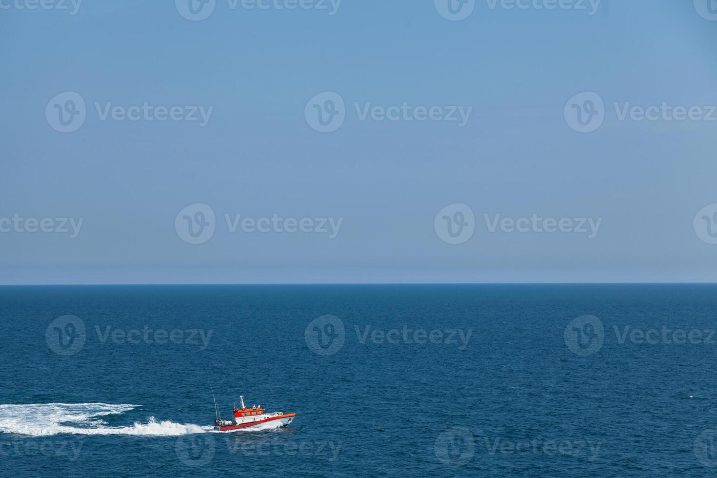 Search and rescue boat floats on the waves at speed. The horizon is visible in the distance. Sky and sea. Light blue back. photo