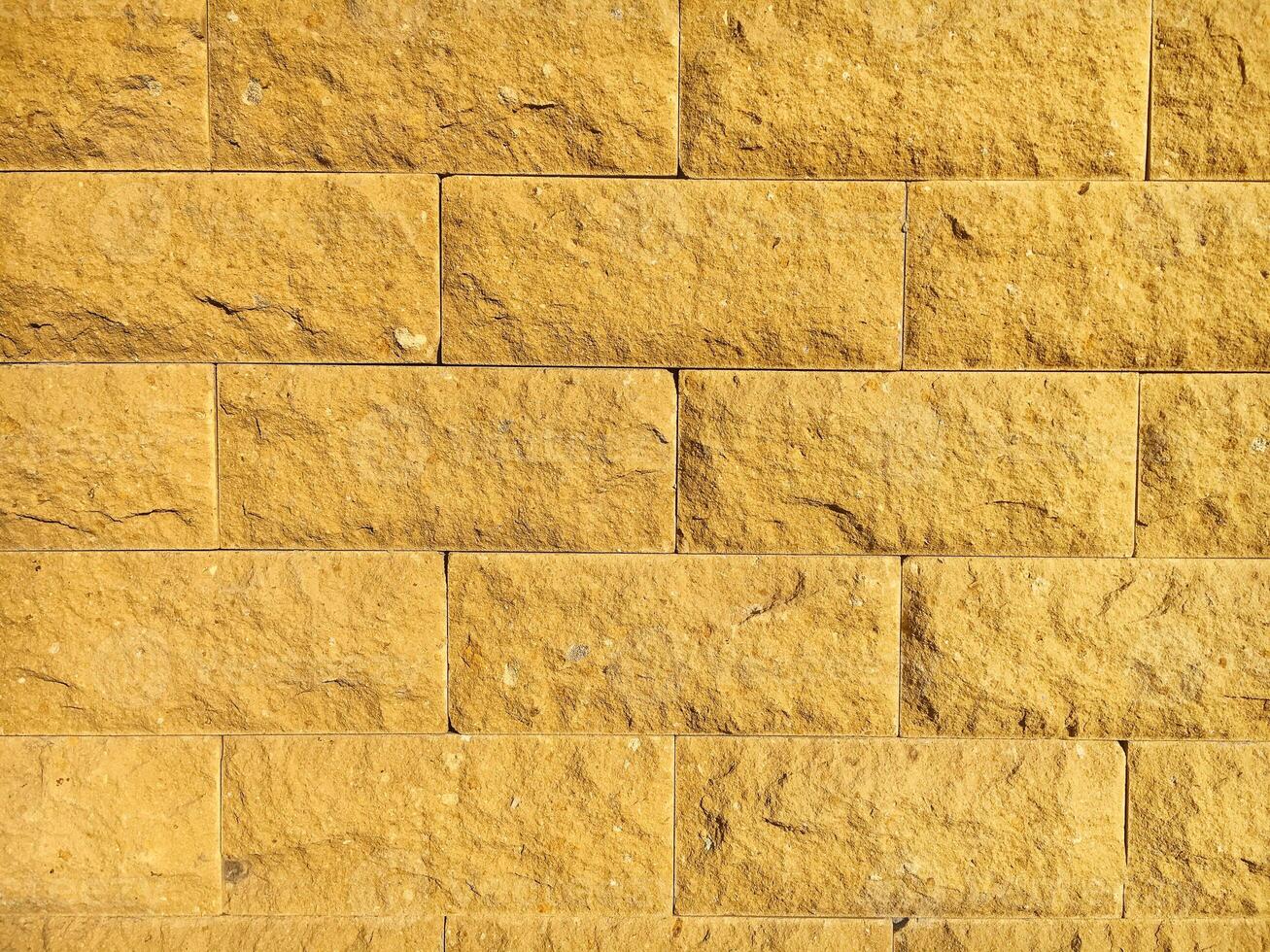 The texture of a rough brick wall. Yellow stone background. photo