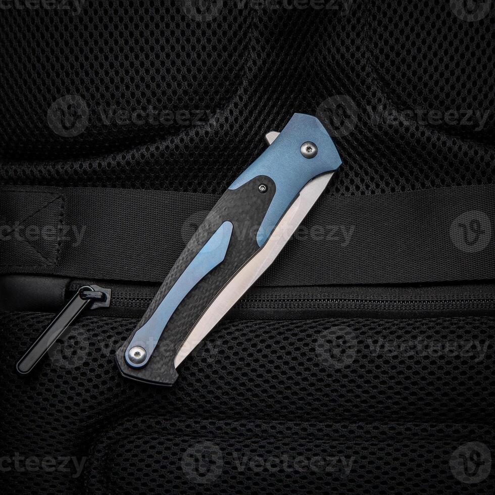 Folding pocket knife with a clip on a dark back. Handle with carbon and color inserts. photo