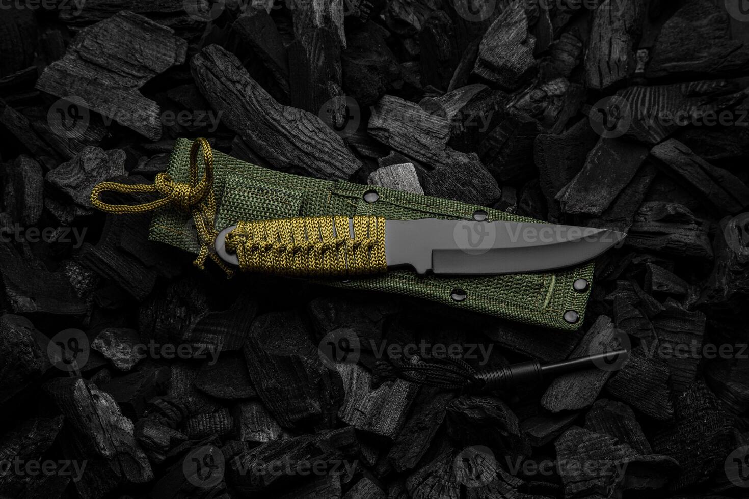 A modern knife with a black blade and a paracord-wrapped handle. Soft green scabbard. Dark charcoal back. photo
